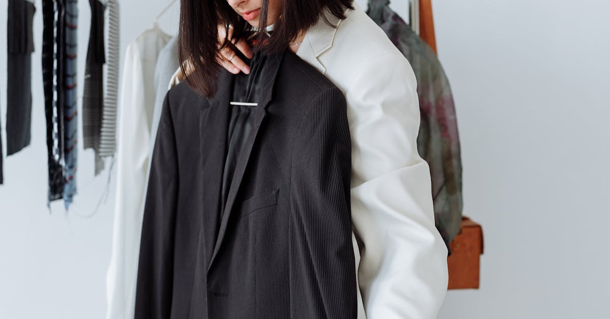 Woman selecting a black blazer in a modern fashion store setting.